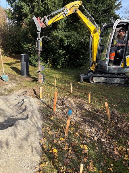Bauhofmitarbeiter legen mit einem Bagger neue Baumgräber an